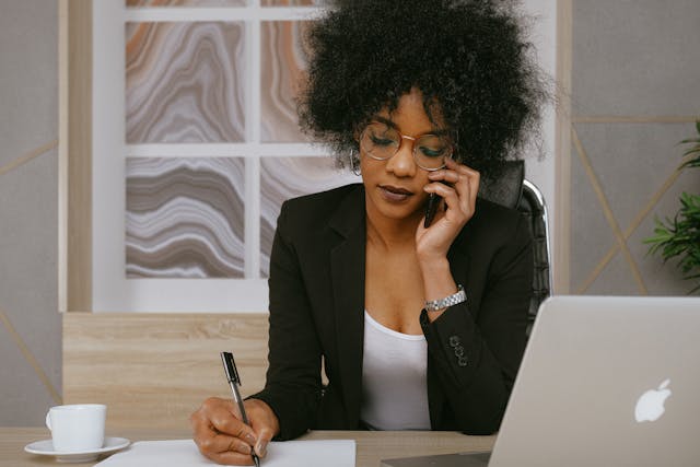 Person talking on the phone while writing with a pen